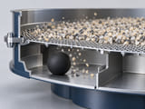Konzeptionelle CGI-Darstellung: Abschnitt eines Industriesiebs mit einer mattschwarzen Gummireinigungskugel in einem Fach unter dem Siebgewebe; ausreichend Freiraum für die sanfte Bewegung der Kugel; saubere, abstrakte Industrieszene ohne sichtbare Körner