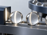 Conceptual CGI: Clear soda-lime glass sphere lit by a narrow bright inspection stripe beside another sphere with a subtle internal bubble shown as a rejected visual concept; no labels or claims